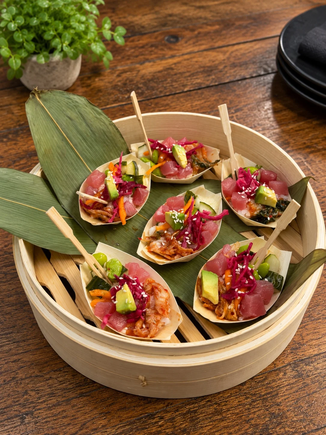 Individual bowl-food portions presented in bamboo boats