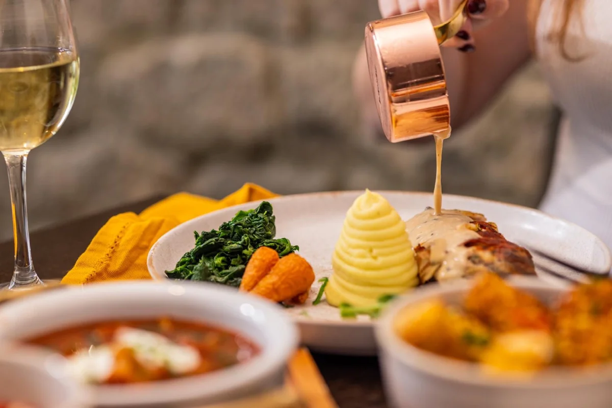 Sauce poured over a plated main with piped potato and vegetables