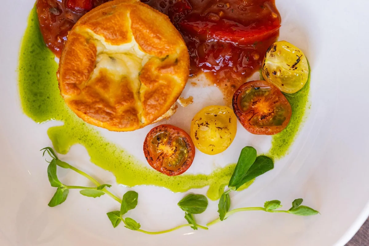Close-up of a plated soufflé with tomatoes and herbs
