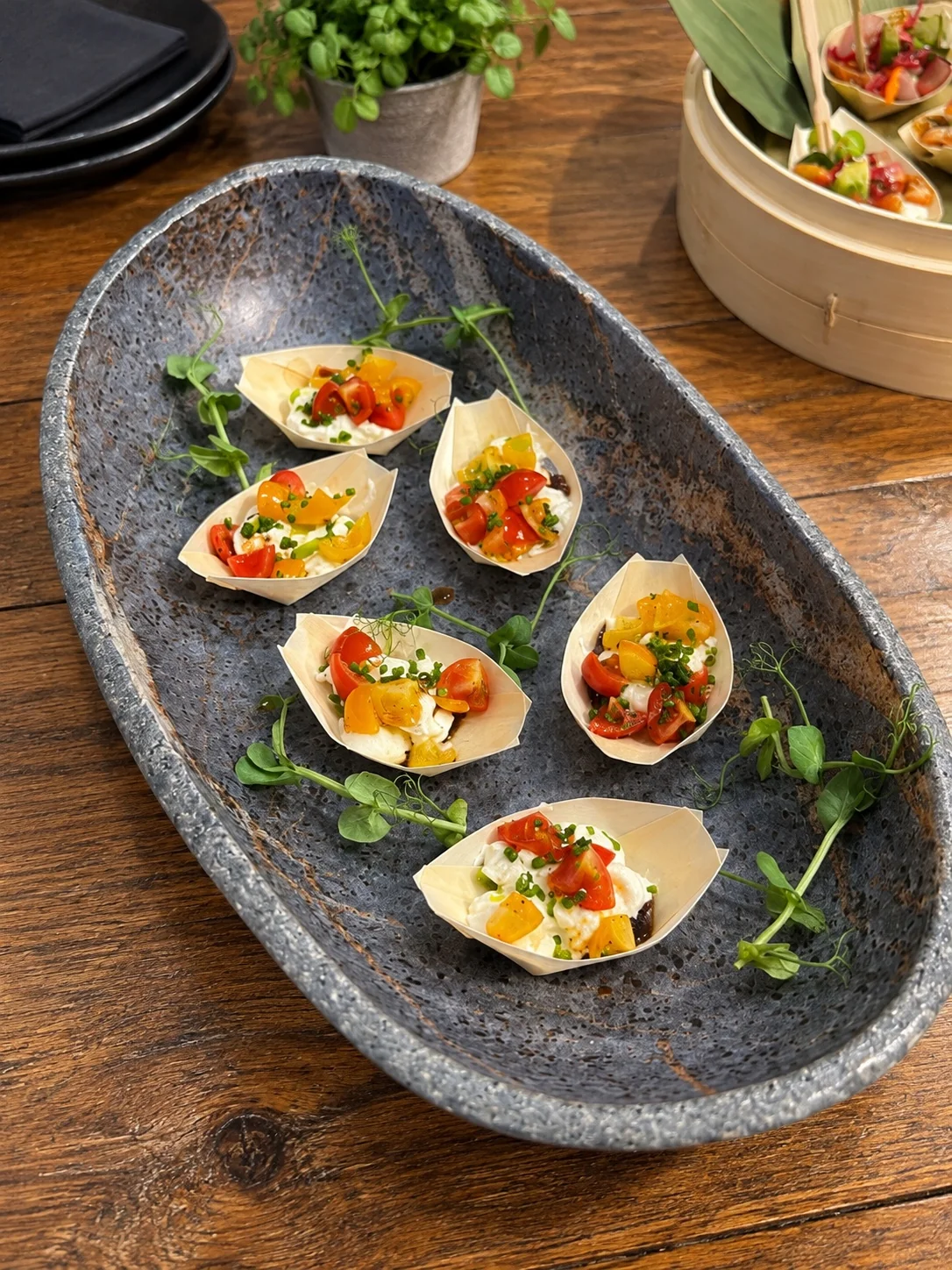 Colourful cherry tomatoes and soft cheese in individual serving boats